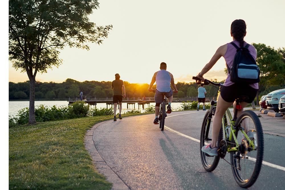 Bikers and runners doing sports over a trail in White Rock lake, Texas during sunset time. De-scale period.